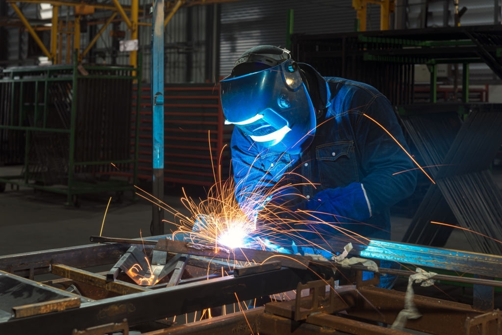 Close-up of a Industrial Welder holding welding Torch with welding sparks.